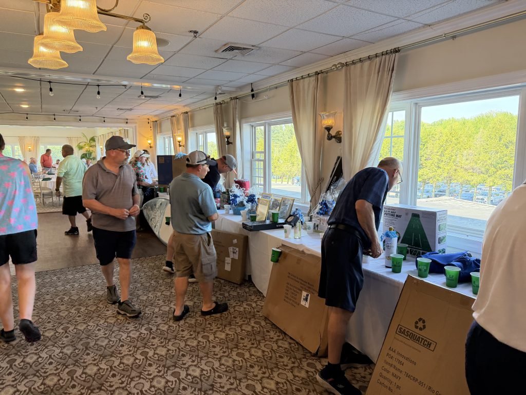 Golf tournament participants looking over raffle prizes inside the clubhouse.