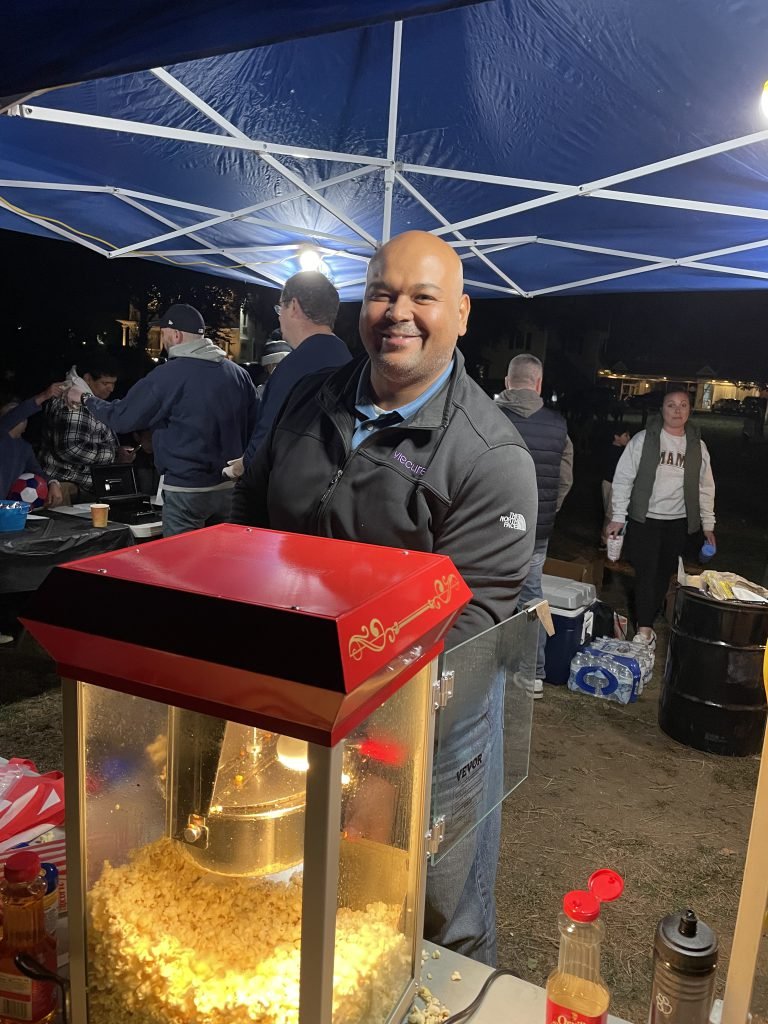 A Movie Night volunteer serves popcorn at the concession table.