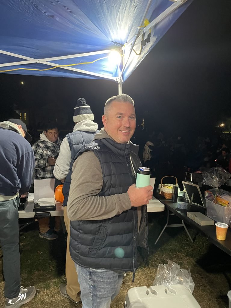 A Movie Night volunteer stands near the concession table with hot chocolate ready for guests.