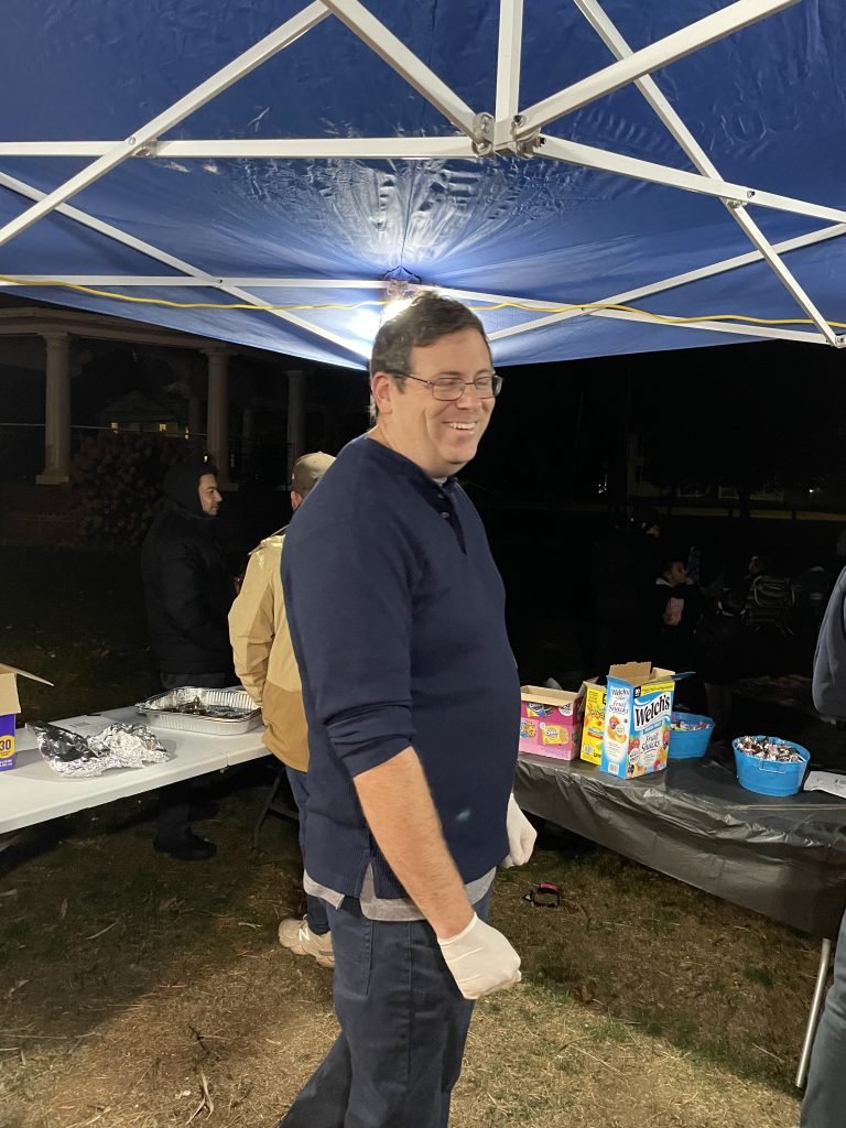 A Movie Night volunteer stands by the snack table during the outdoor event.